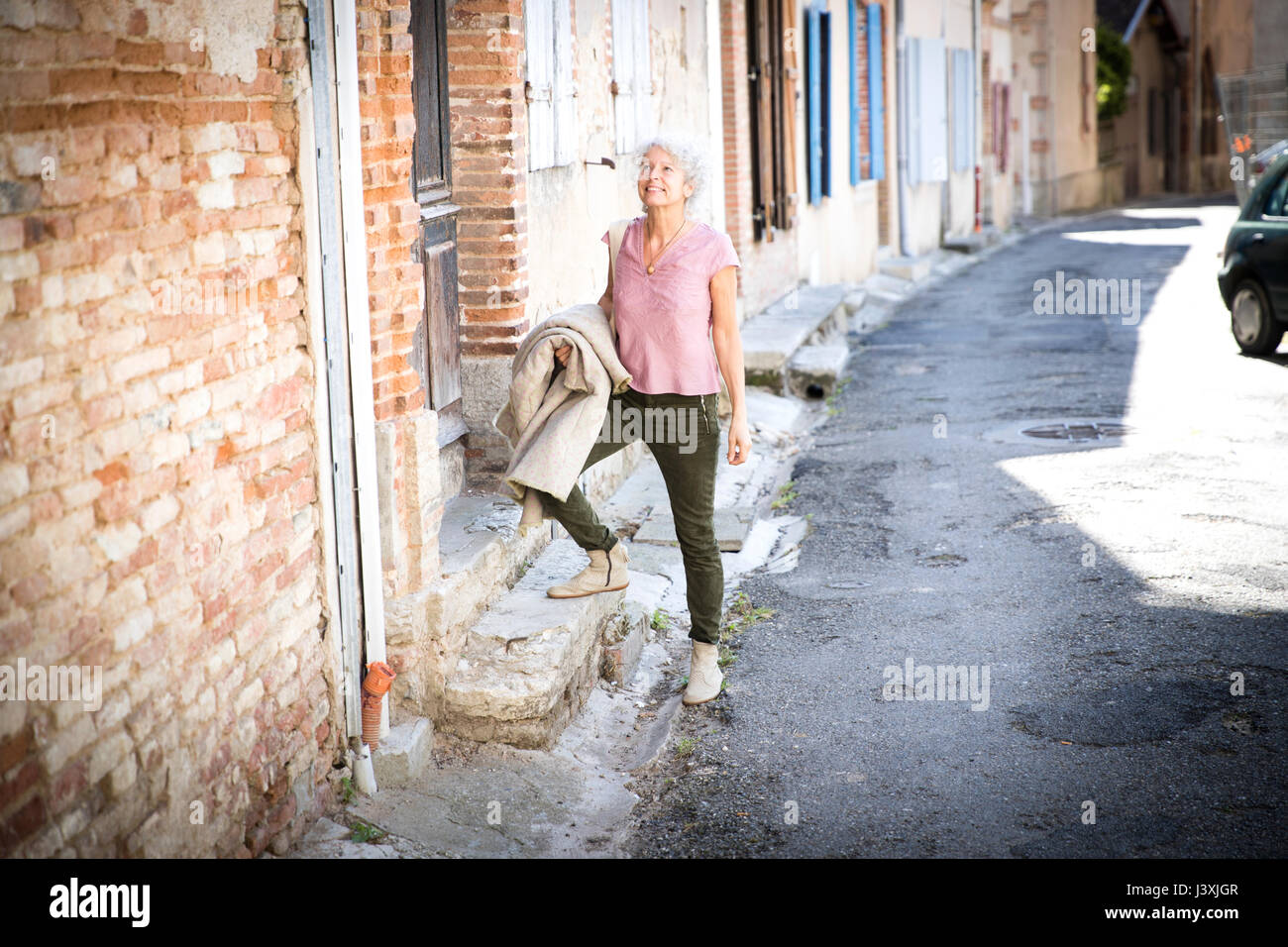 Donna in strada guardando lontano sorridente, Bruniquel, Francia Foto Stock