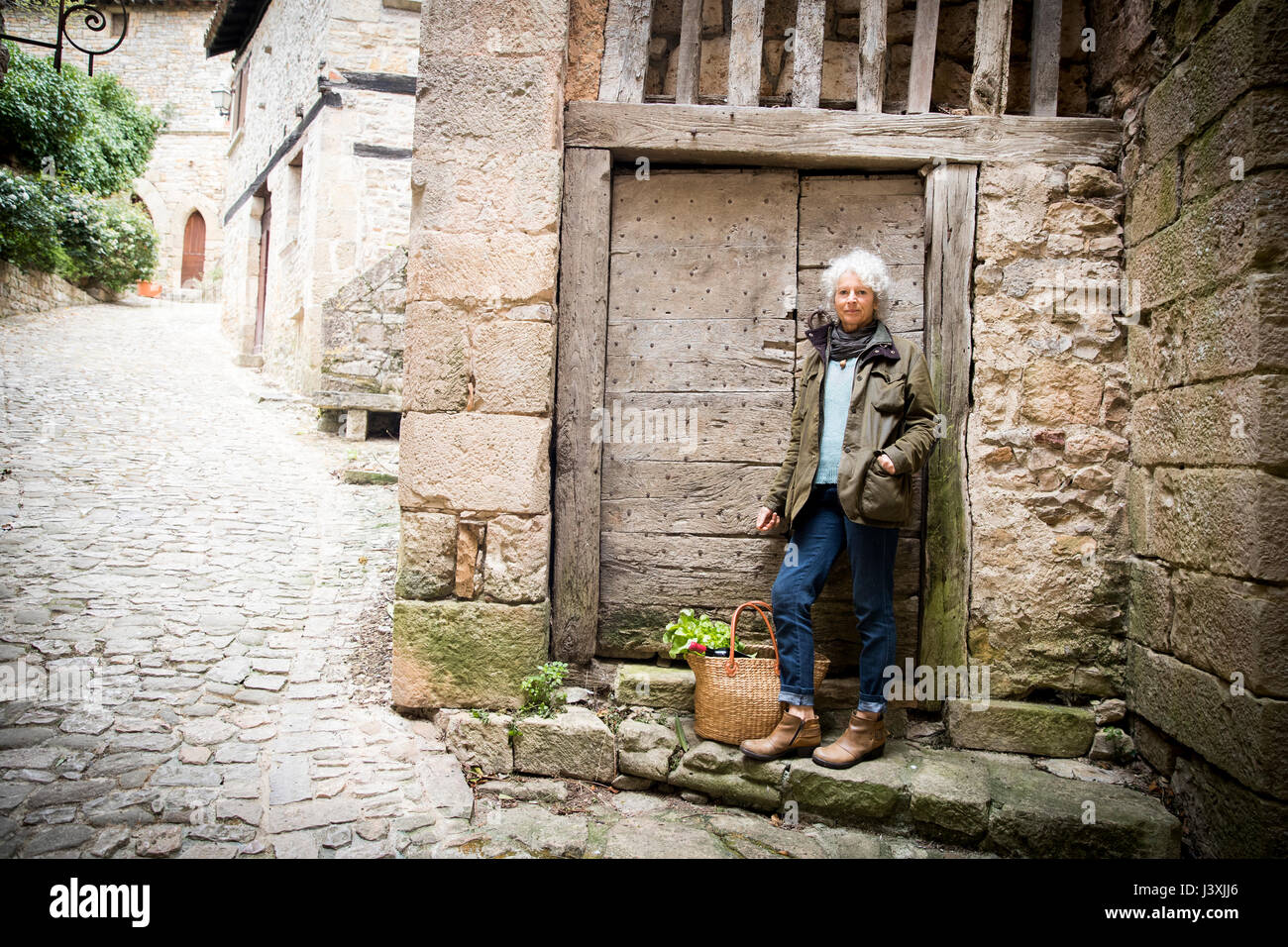 Donna appoggiata contro la porta di legno, Bruniquel, Francia Foto Stock