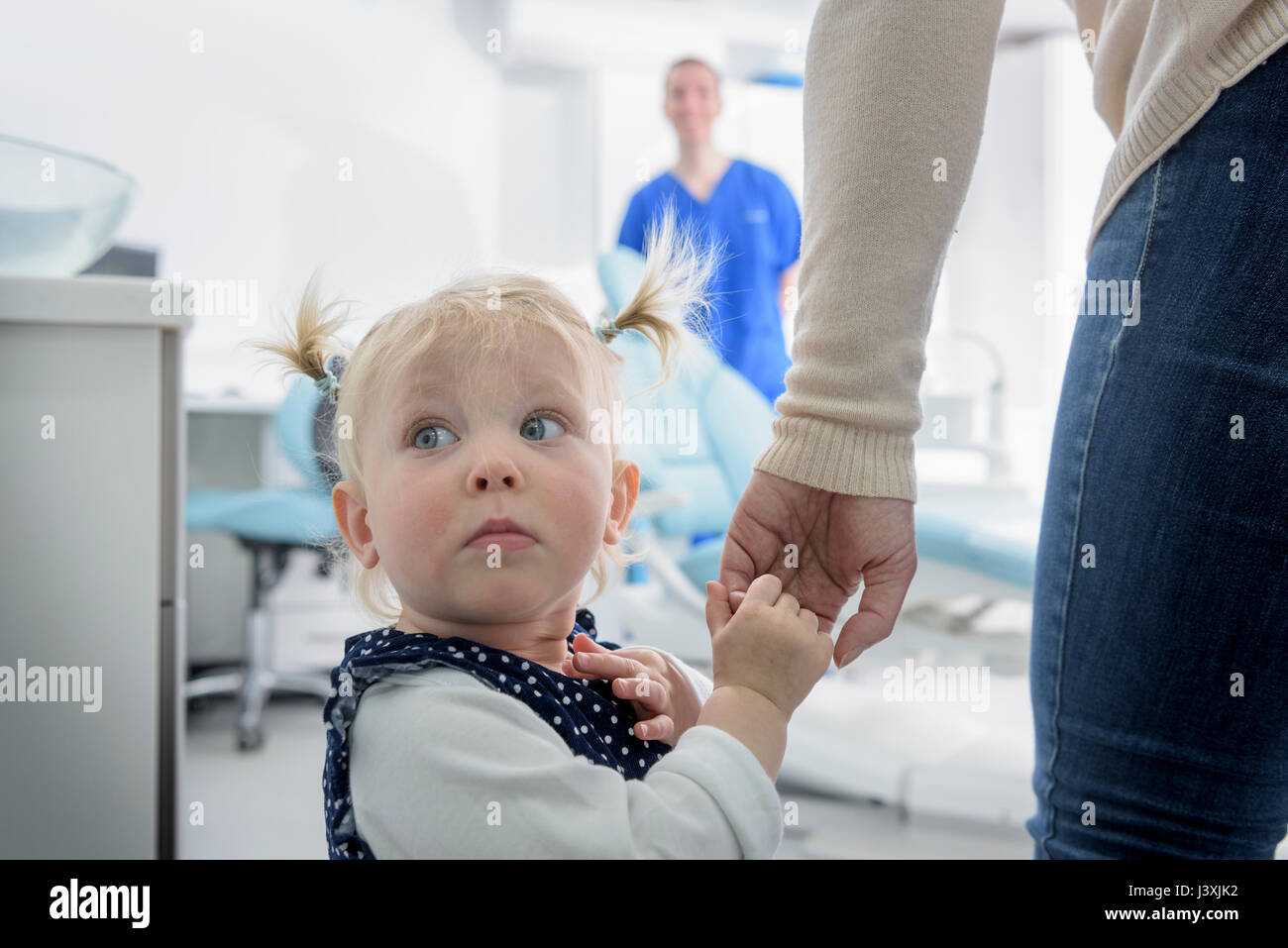 Bambina entrando in chirurgia dentale, guardando lontano Foto Stock