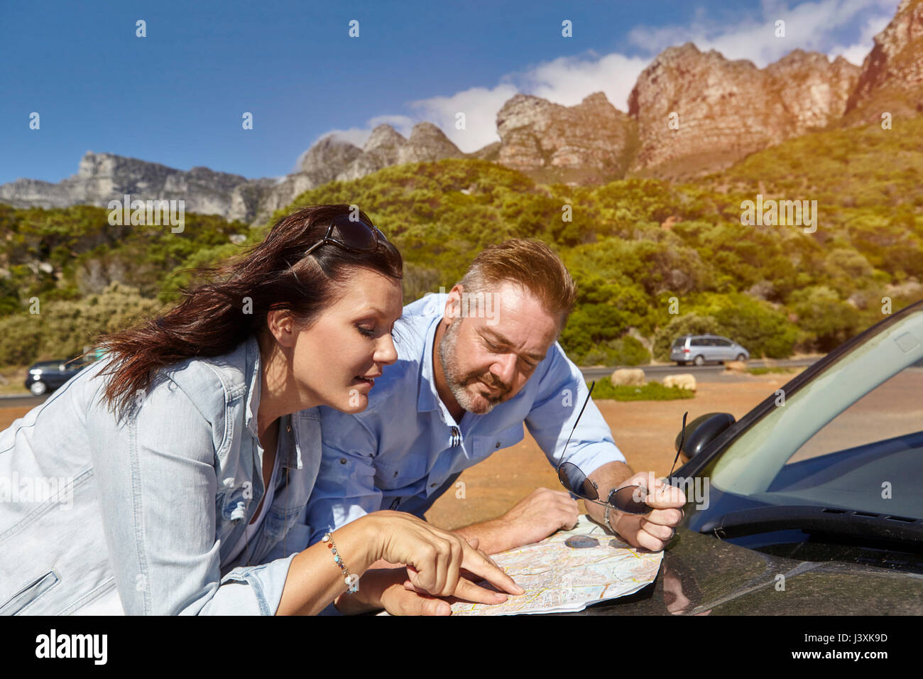 Giovane appoggiata sul cofano auto, guardando la mappa, Città del Capo Foto Stock