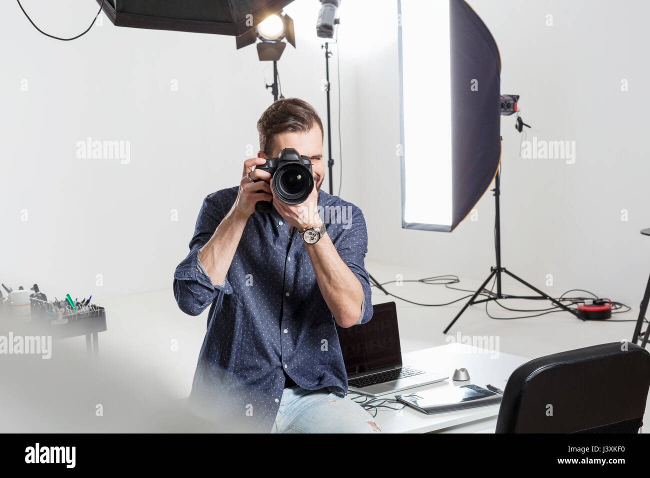 Fotografo maschio test concentrarsi sulle reflex digitali in studio fotografico Foto Stock