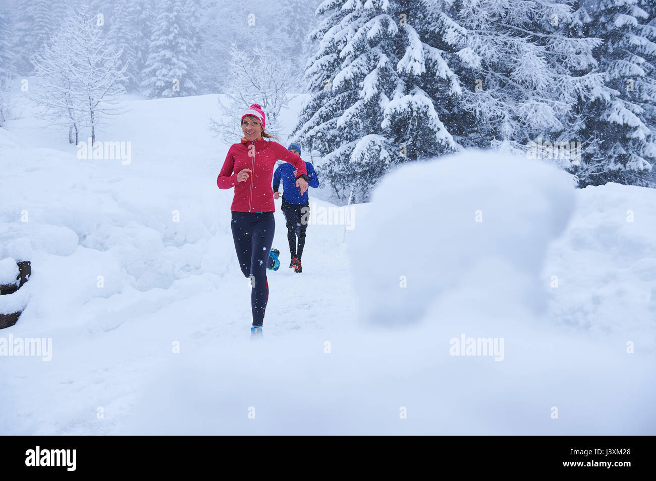 Maschi e femmine di corridori in esecuzione sulla via nella neve profonda, Gstaad, Svizzera Foto Stock