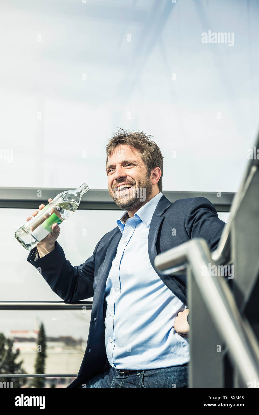 Imprenditore di bere acqua in bottiglia sulla scalinata di office Foto Stock