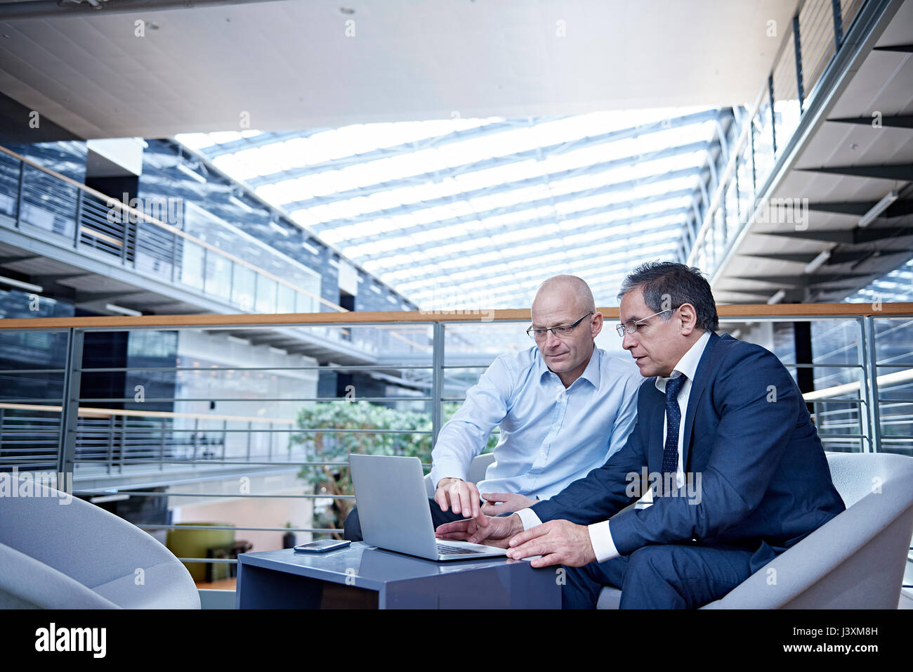 Due imprenditori matura guardando il laptop in riunione sul balcone di office Foto Stock
