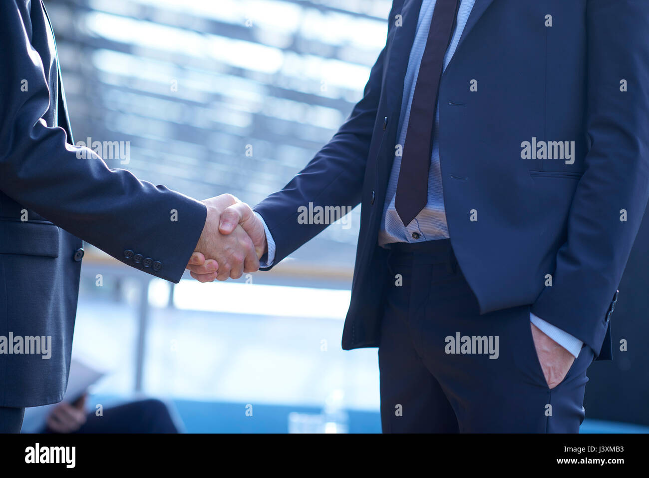 La sezione centrale di due imprenditori stringono le mani in office atrium Foto Stock