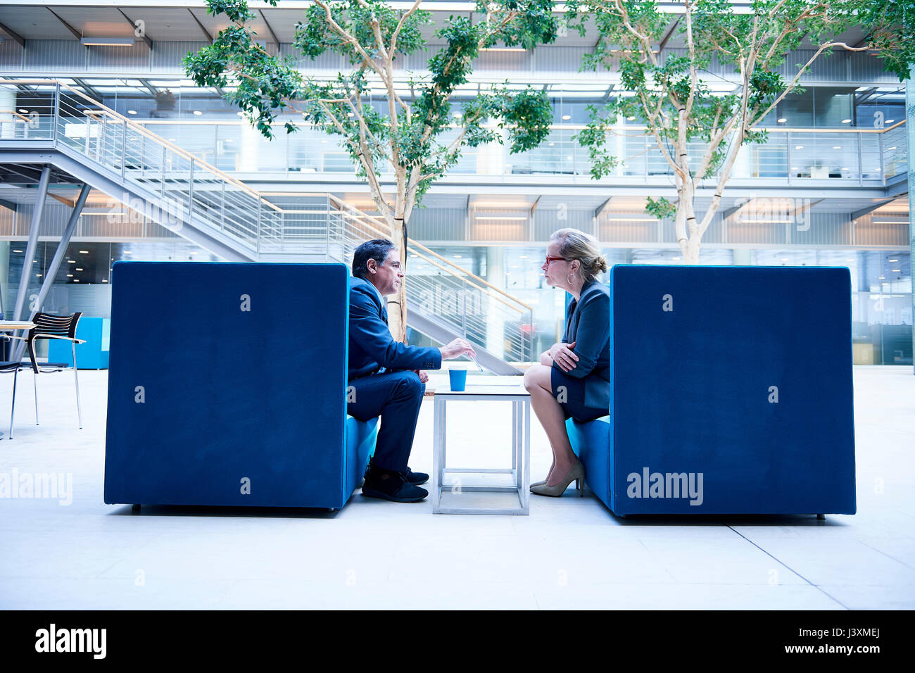 Imprenditrice e l uomo alla riunione in ufficio Poltrone atrium Foto Stock