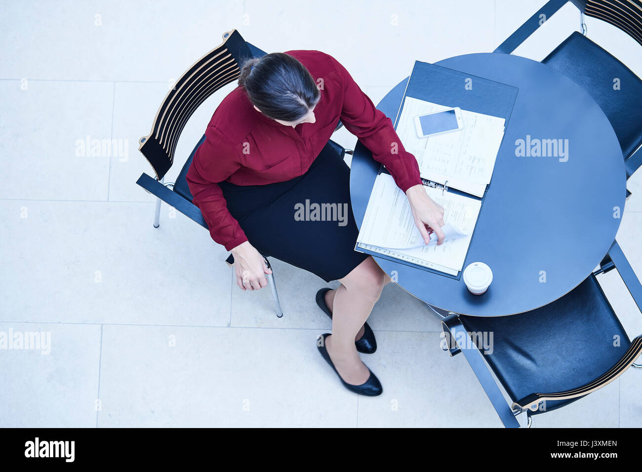 Vista aerea di imprenditrice la lettura di documenti cartacei a tavola in office atrium Foto Stock