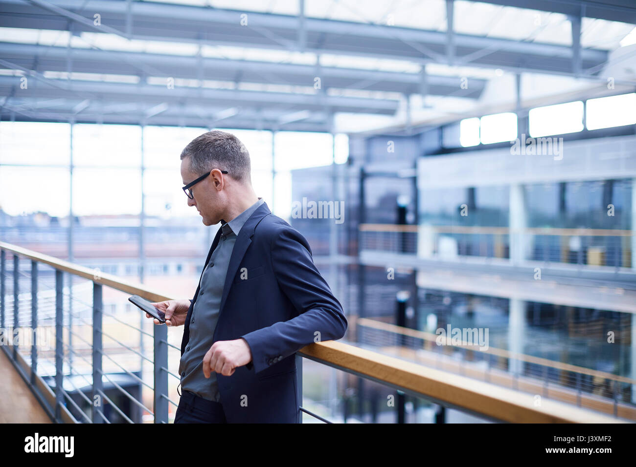 Imprenditore guardando smartphone sul balcone di office Foto Stock