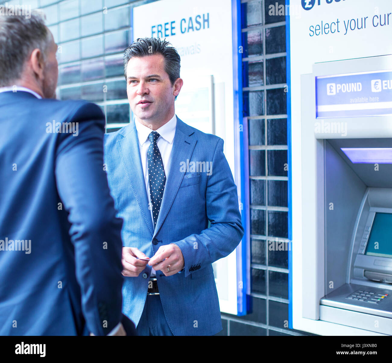 Imprenditori parlando dal bancomat Foto Stock