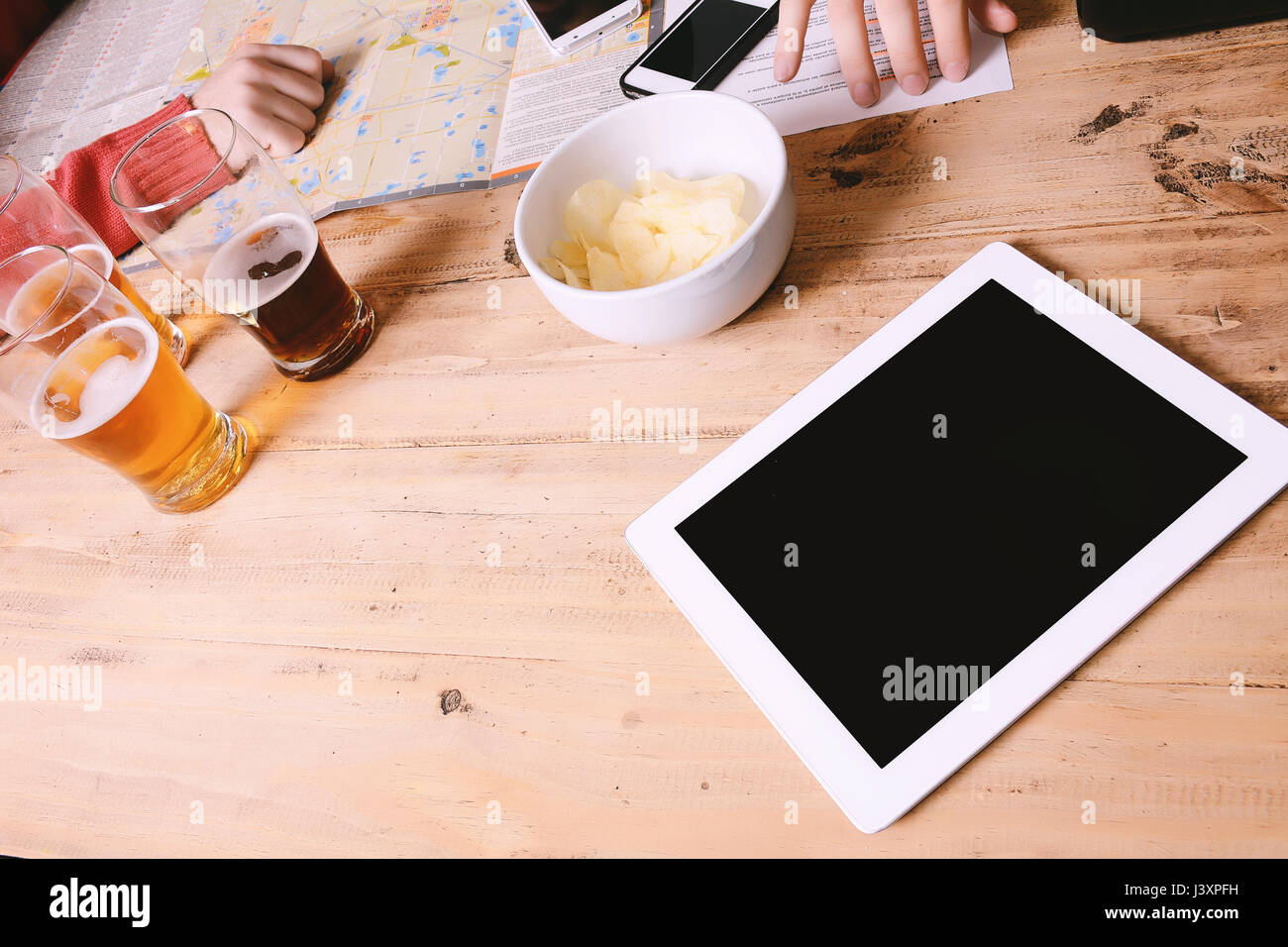 Un gruppo di giovani amici di esplorare la mappa con il tablet e birra. Concetto di vacanza Foto Stock