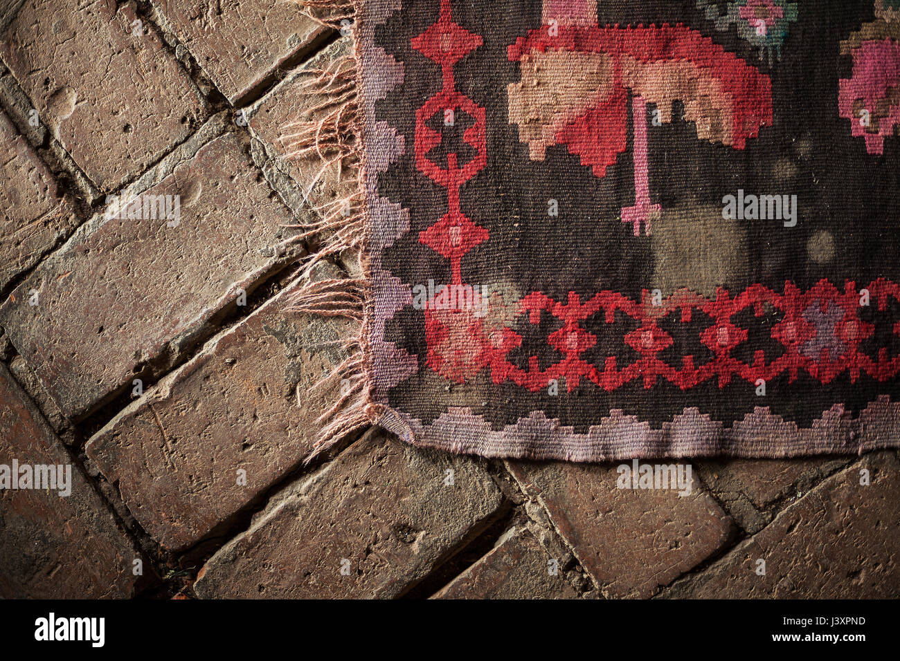 Dettagli di un vecchio ricami tappeto sul pavimento in cotto. Foto Stock