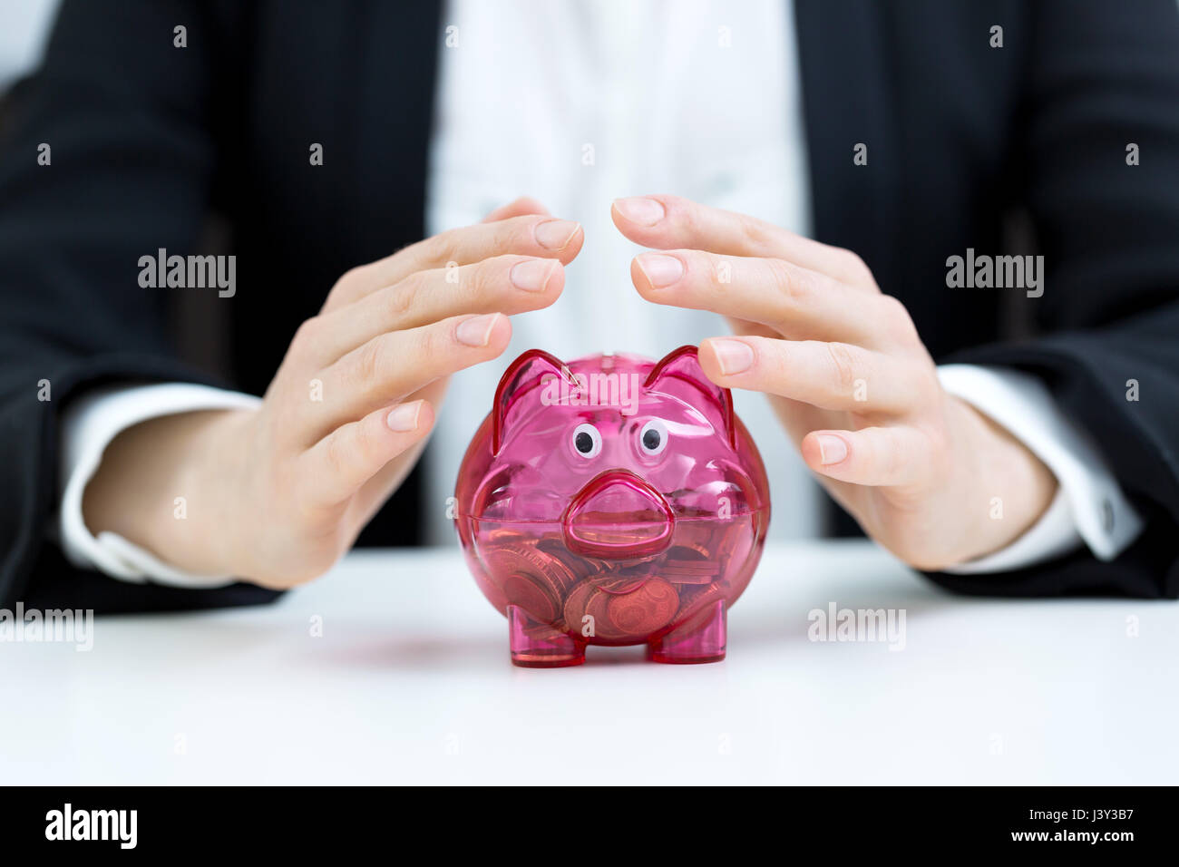 Business concetto di risparmio - imprenditrice a copertura salvadanaio con le mani Foto Stock