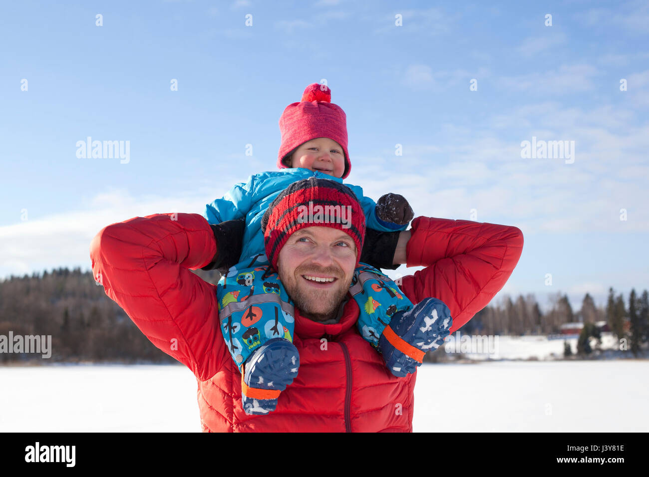 Padre che trasportano giovane figlio sulle spalle, in paesaggi innevati Foto Stock