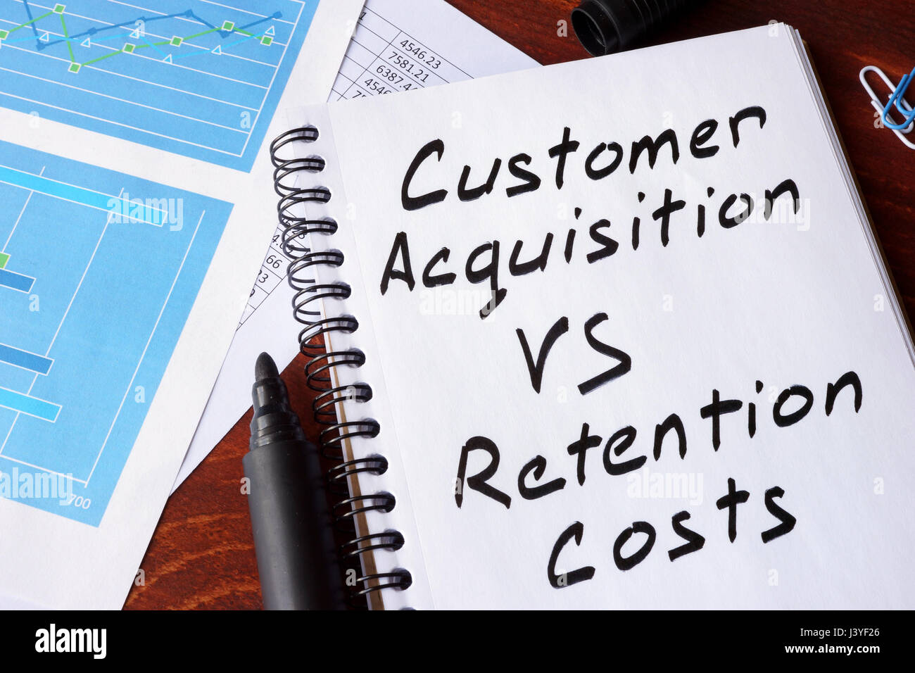 Acquisizione di clienti vs costi di ritenuta scritto in una nota. Foto Stock