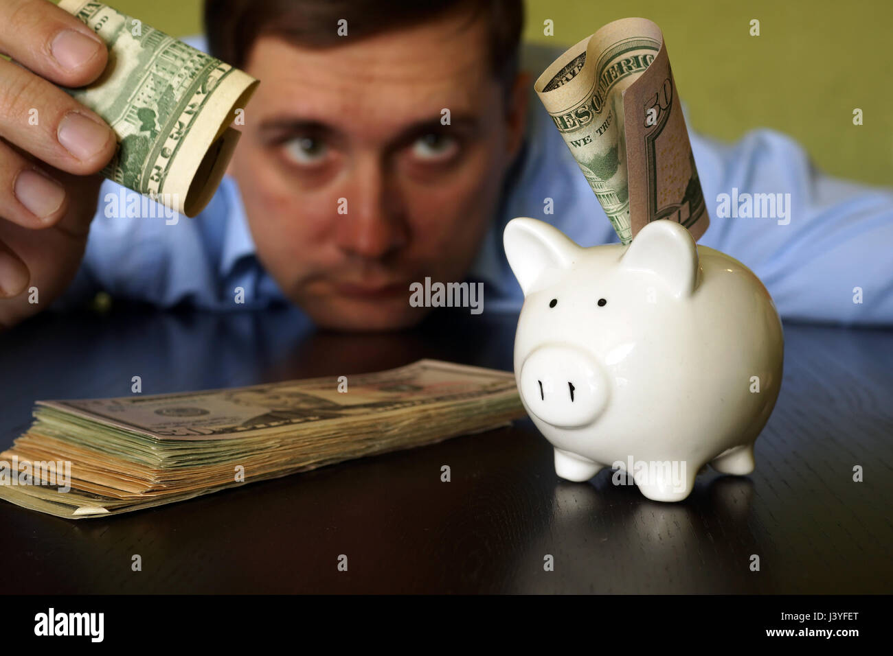 Uomo di mettere moneta nel salvadanaio. Il concetto di risparmio. Foto Stock