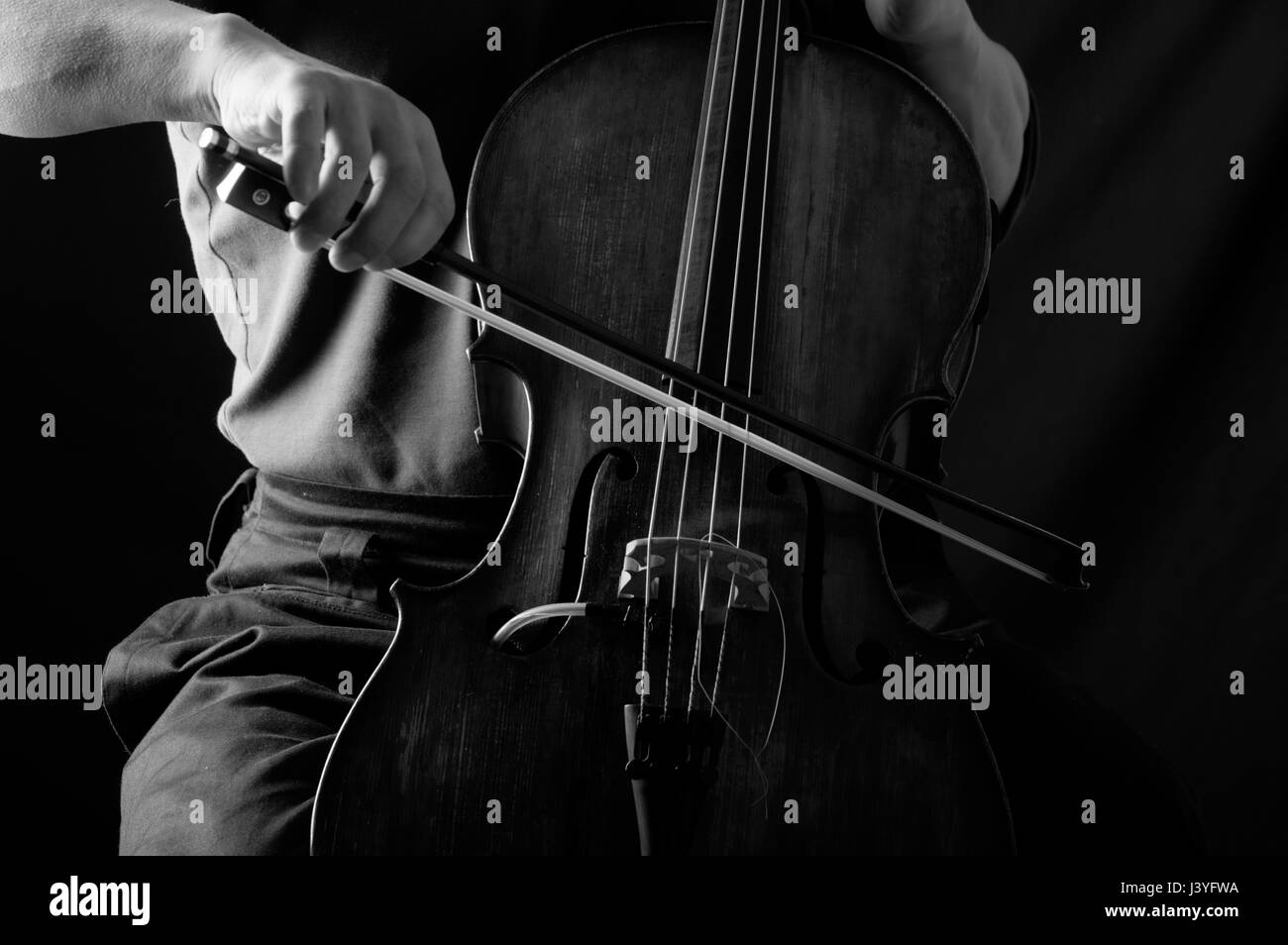 Fotografia in bianco e nero di un uomo in violoncello con un inchino, il suo volto nascosto Foto Stock