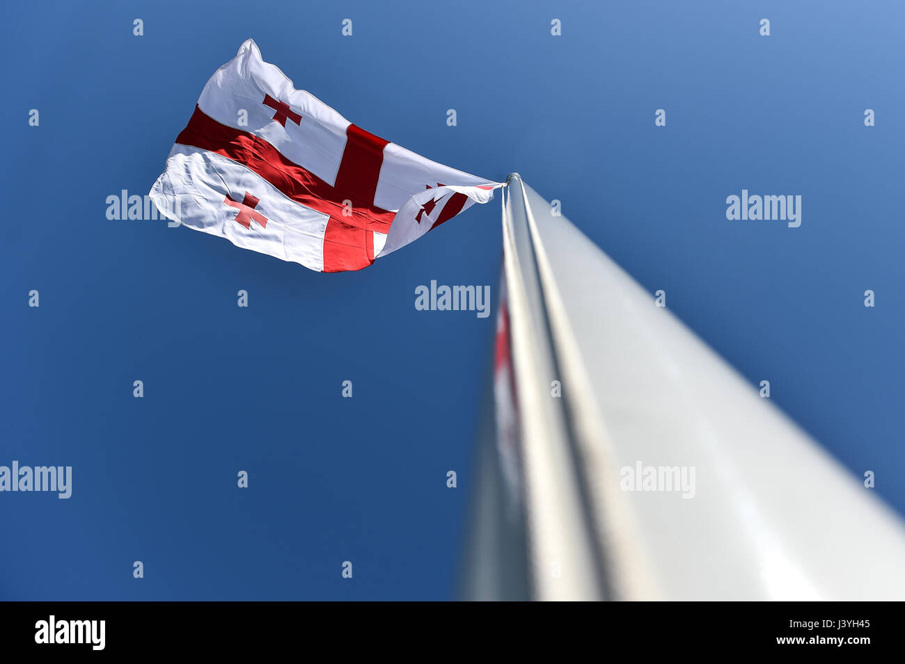 La Georgia bandiera nazionale soffiata dal vento contro un cielo blu Foto Stock