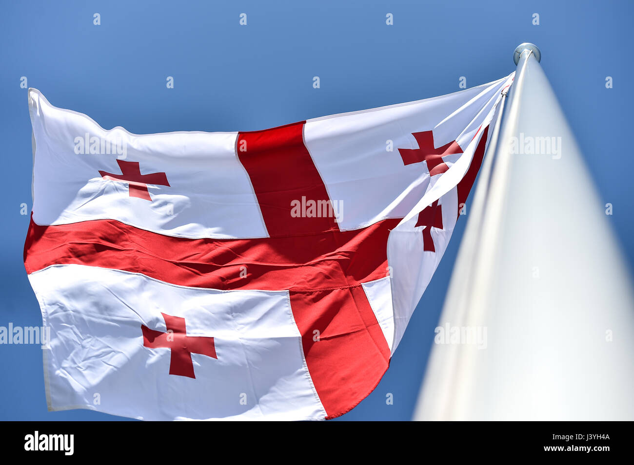 La Georgia bandiera nazionale soffiata dal vento contro un cielo blu Foto Stock