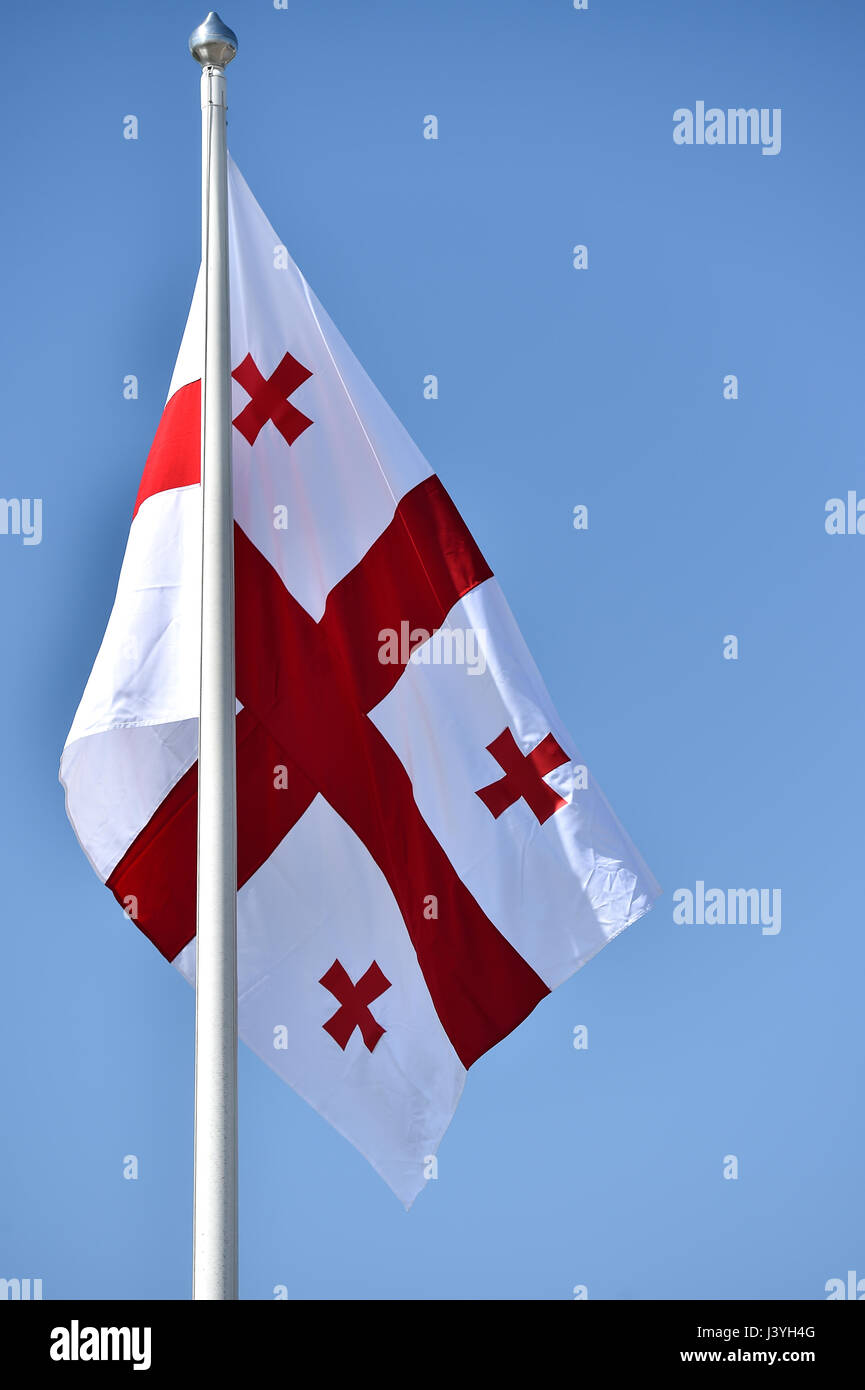 La Georgia bandiera nazionale soffiata dal vento contro un cielo blu Foto Stock