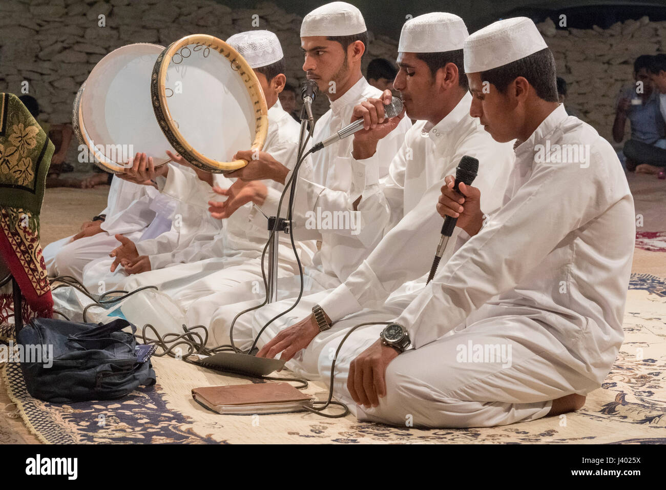 Giovani uomini cantando canti religiosi con Drims sotto una tenda di lunedì sera la prima notte di nozze tradizionale, Tabl, isola di Qeshm, Hormozgan P Foto Stock