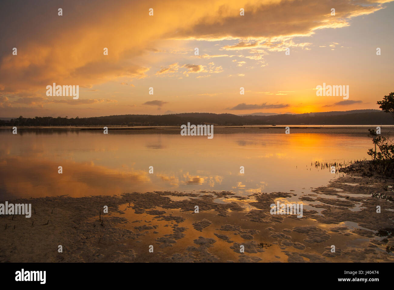 Merimbula lago ha spesso magici tramonti. Come la marea riempie la concavità a sinistra sulla sabbia i riflessi delle nuvole appaiono. Foto Stock
