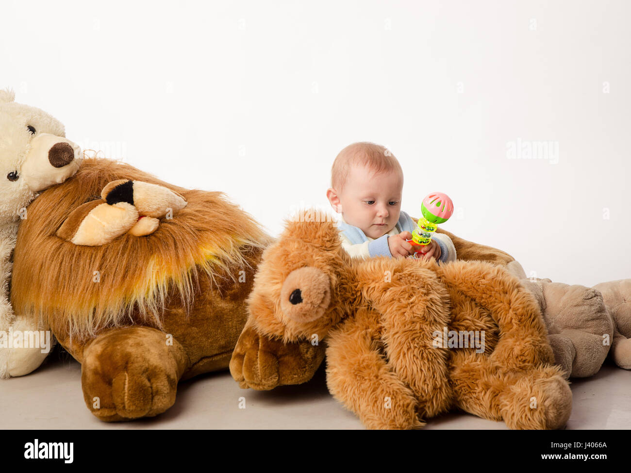 Bambina si siede tra i tanti giocattoli di peluche Foto stock - Alamy