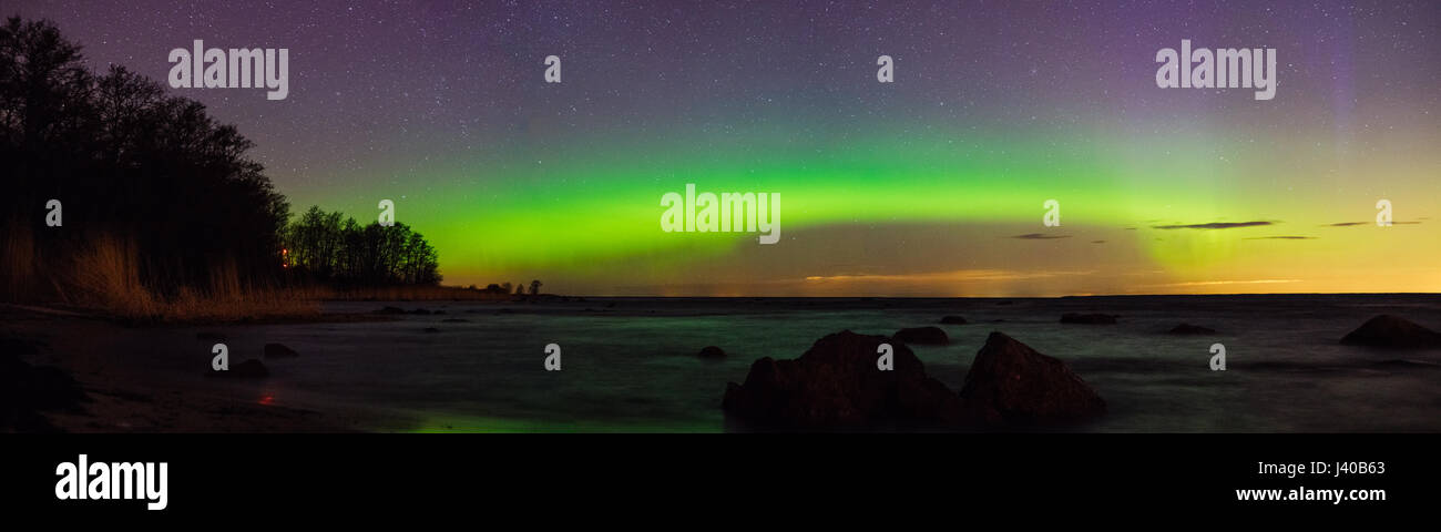 Cielo stellato e aurora boreale su pietroso riva del mare, vista panoramica Foto Stock