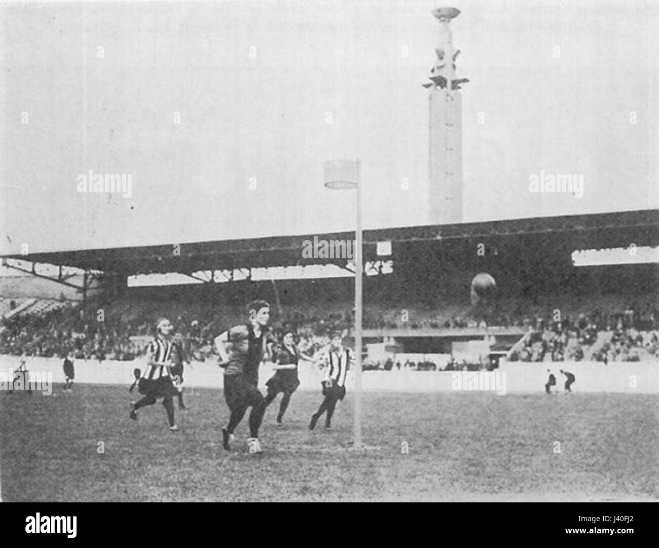 Questa immagine raffigura un momento di una partita di Korfball del 1928, che mostra l'azione e l'atletismo di questo sport di squadra. Il Korfball, uno sport di origine olandese, è caratterizzato da squadre di genere misto e mira a segnare lanciando una palla in un cerchio. Foto Stock