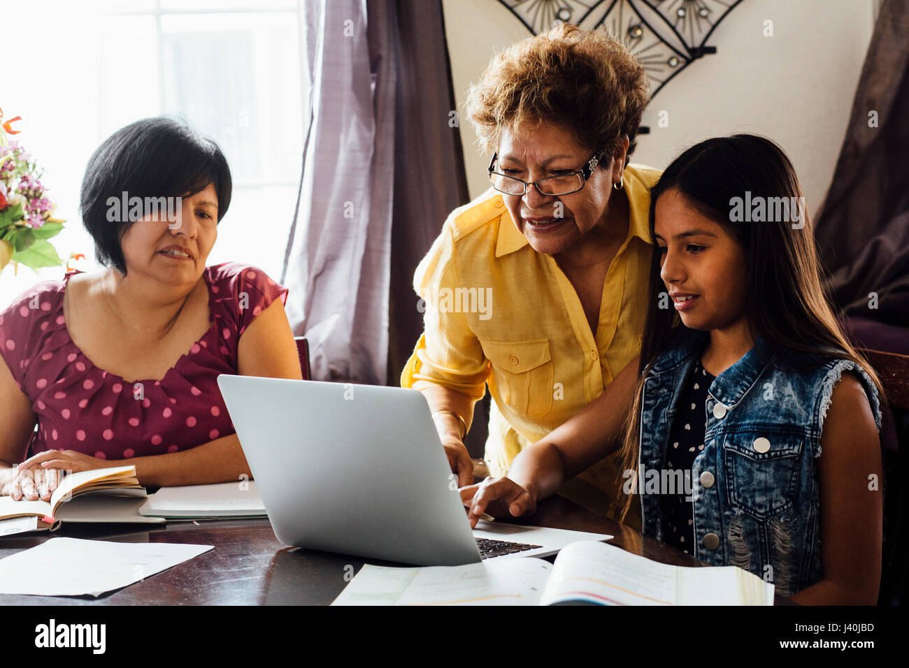 Madre e nonna aiutando la ragazza con compiti utilizzando laptop Foto Stock