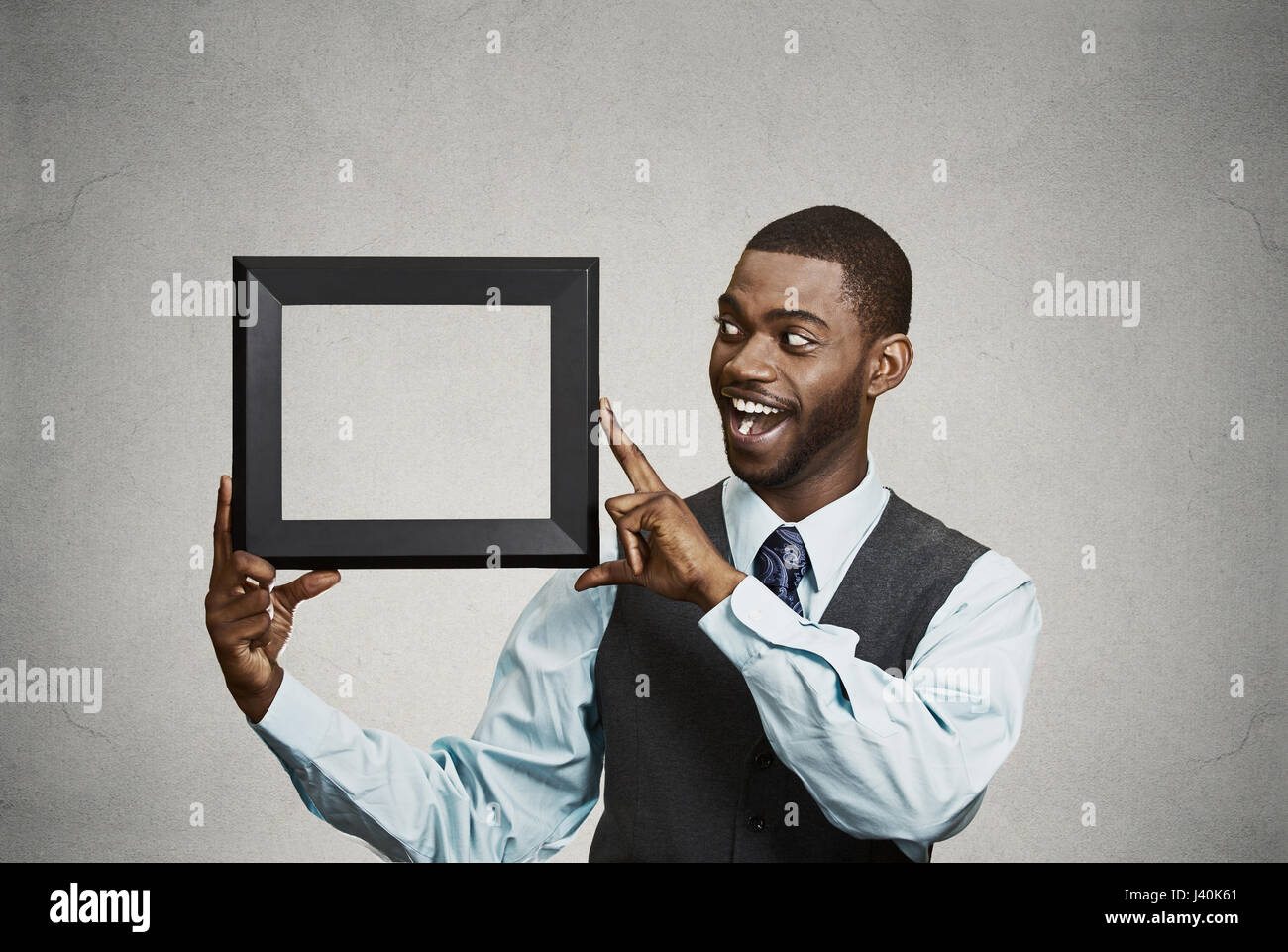 Closeup ritratto sorridenti fiducioso bello azienda imprenditore, corporate executive azienda vuota cornice nera con copia spazio. Positivo Foto Stock