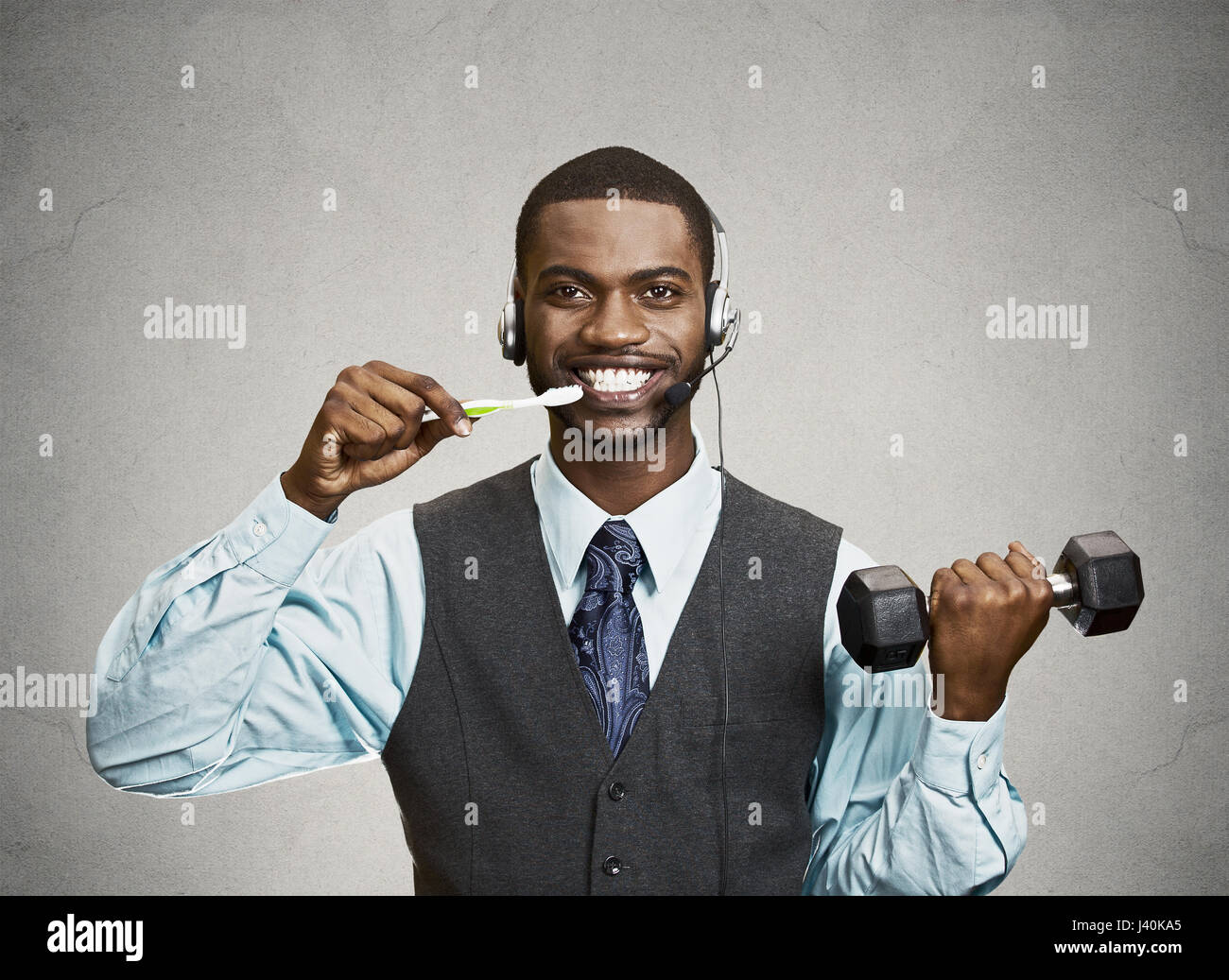Nozione di imprenditore di multitasking. Closeup ritratto corporate business man parlando al telefono, spazzolare i denti e il sollevamento di pesi isolato muro grigio bac Foto Stock