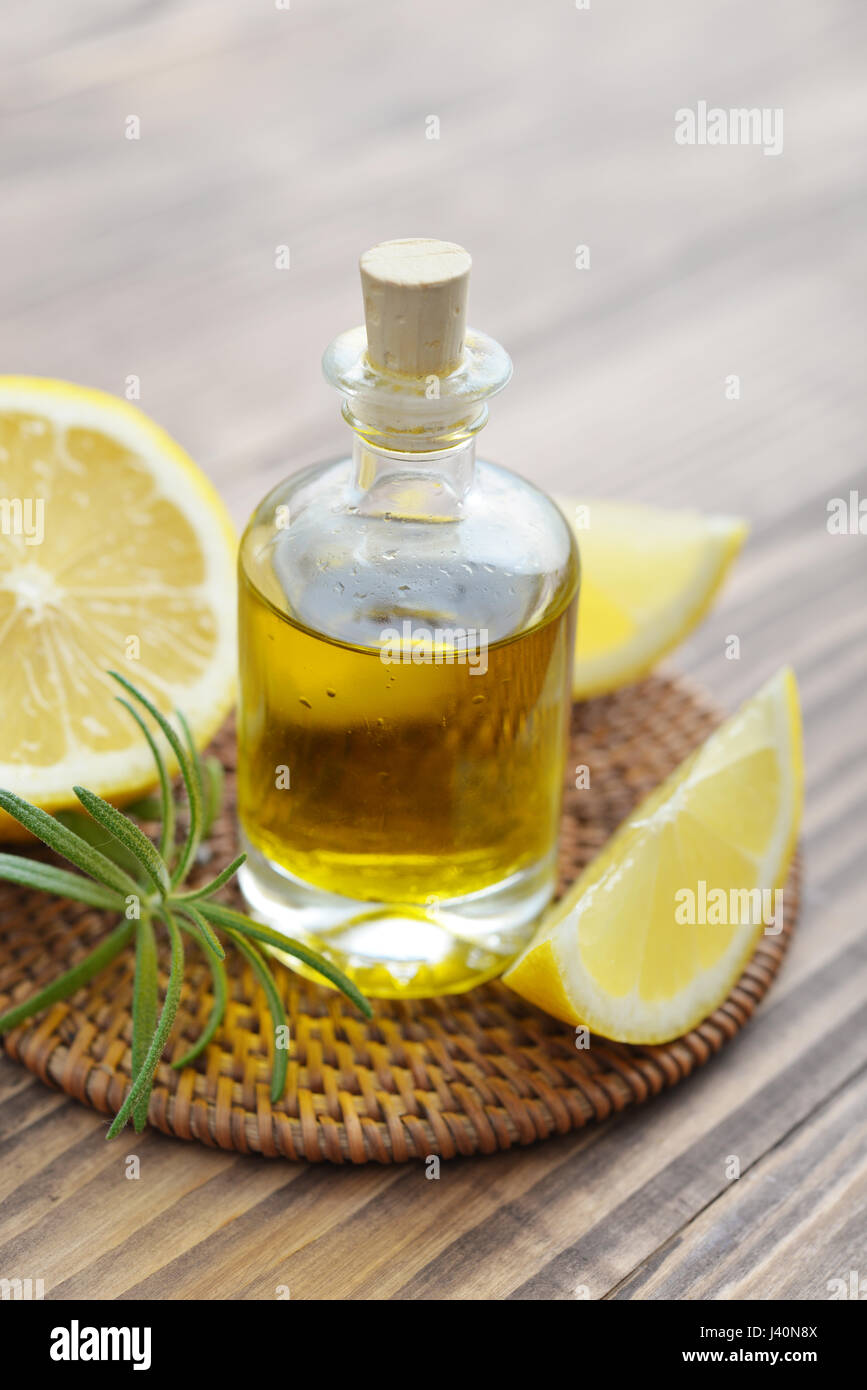 Olio di limone in una bottiglia di vetro con limone fresco su sfondo di legno closeup Foto Stock