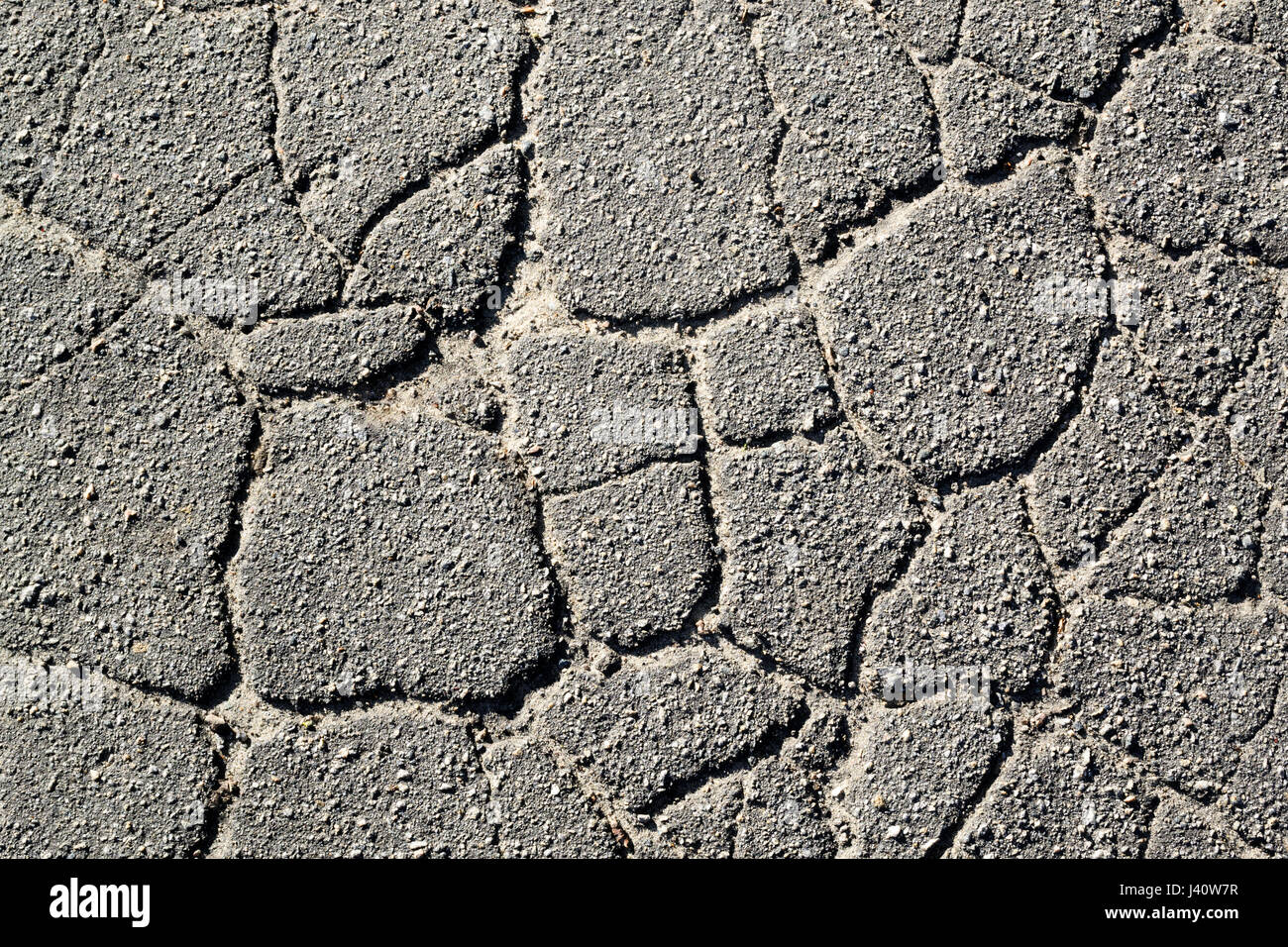 Texture di vecchio asfalto screpolato nelle ore diurne. Sfondo Foto Stock