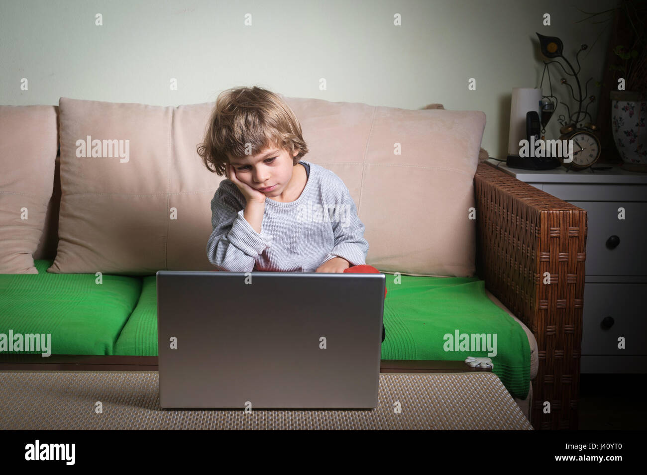 Little Boy annoiato guardare cartoni sul computer. Foto Stock