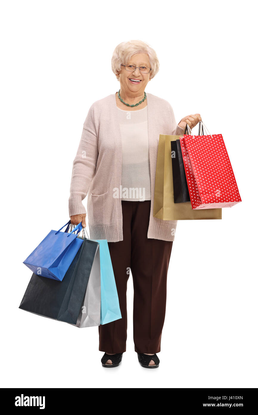 A piena lunghezza Ritratto di una donna anziana con shopping bags guardando la telecamera e sorridente isolati su sfondo bianco Foto Stock