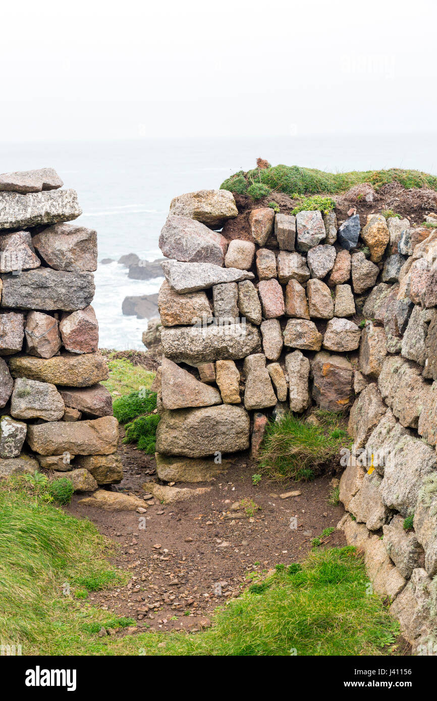 Un squeeze stile in pietra a secco muro costruito da blocchi di granito di diverse dimensioni e colori a Cape Cornwall, Cornwall, Regno Unito Foto Stock