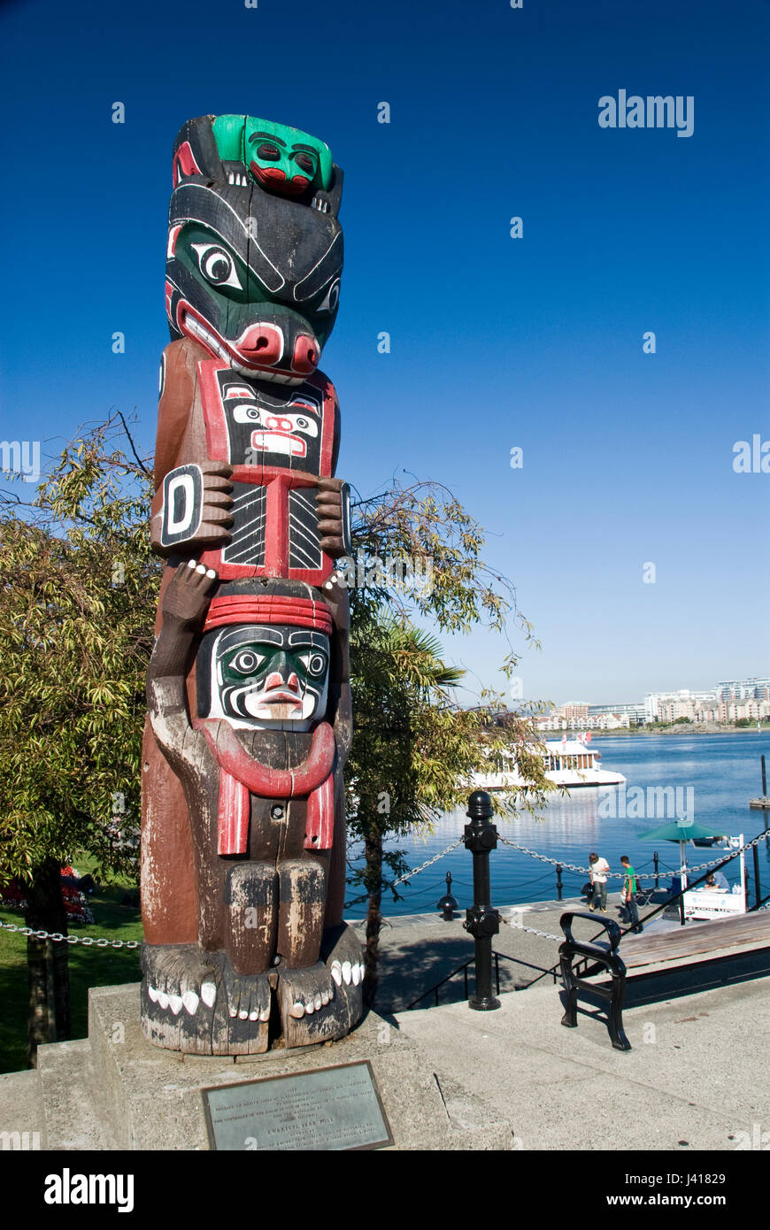 Un indiano in legno totem pole sorge dal porto interno, Victoria, British Columbia, Canada. Foto Stock