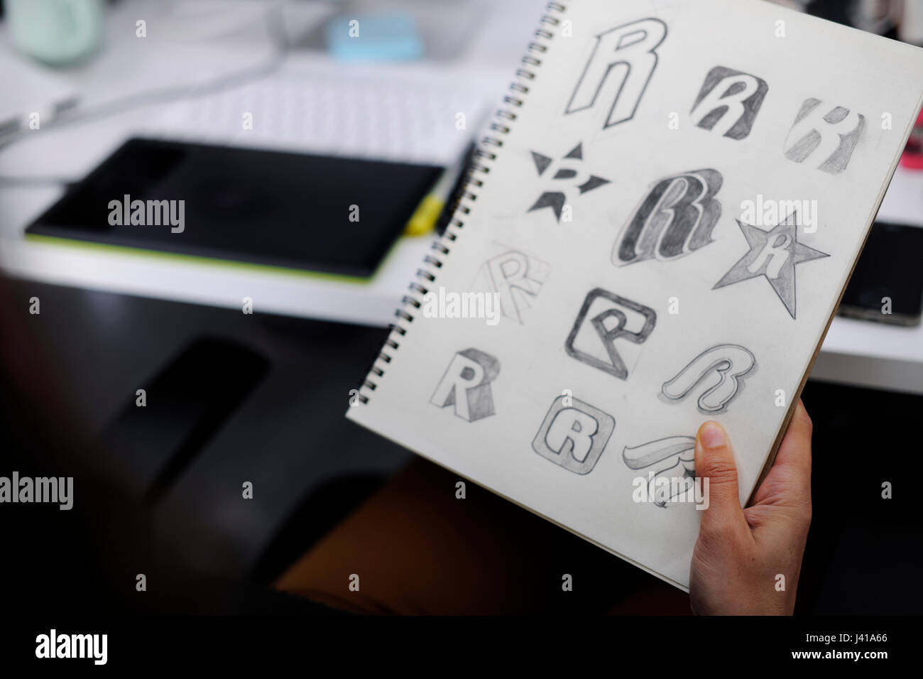 Mano che tiene il notebook con disegnò il Logo del marchio Creative Idee di Design Foto Stock