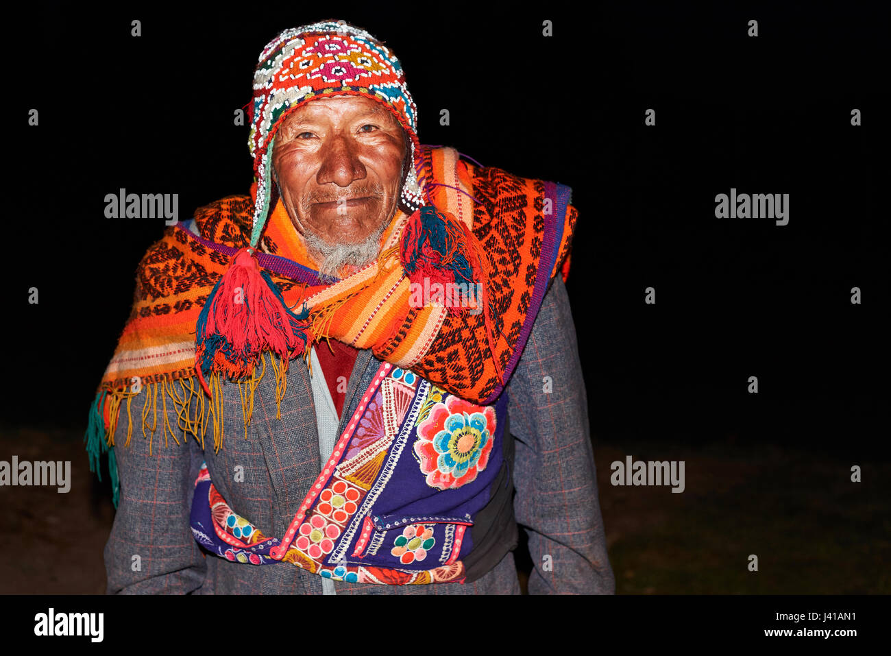 Cusco, Perù- Aprile 20, 2017: Vecchio indio peruviano uomo in colorati abiti tradizionali su nero lo sfondo di strada Foto Stock
