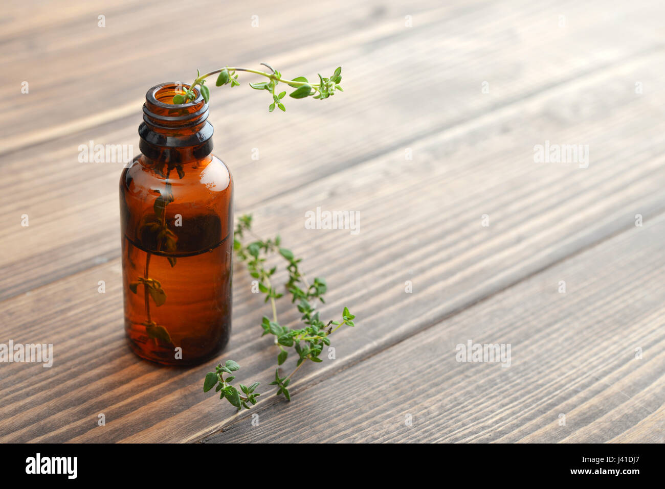 Bottiglia di olio essenziale di timo erbe su sfondo di legno . Foto Stock