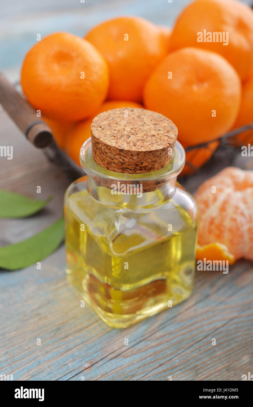 Tangerine olio essenziale in una bottiglia di vetro con freschi Mandarini on- sfondo di legno Foto Stock