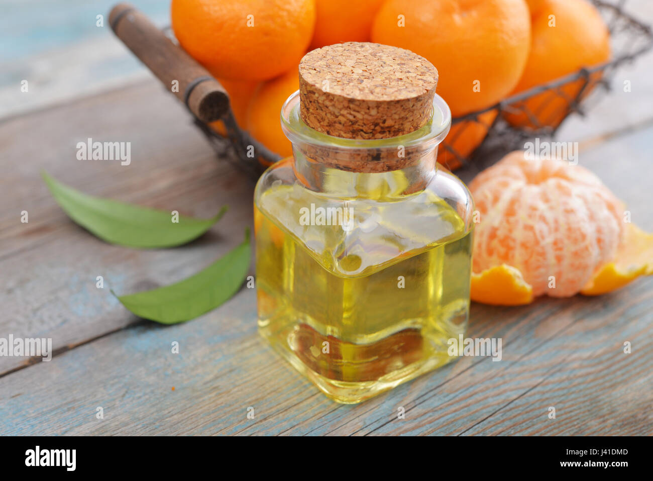 Tangerine olio essenziale in una bottiglia di vetro con freschi Mandarini on- sfondo di legno Foto Stock