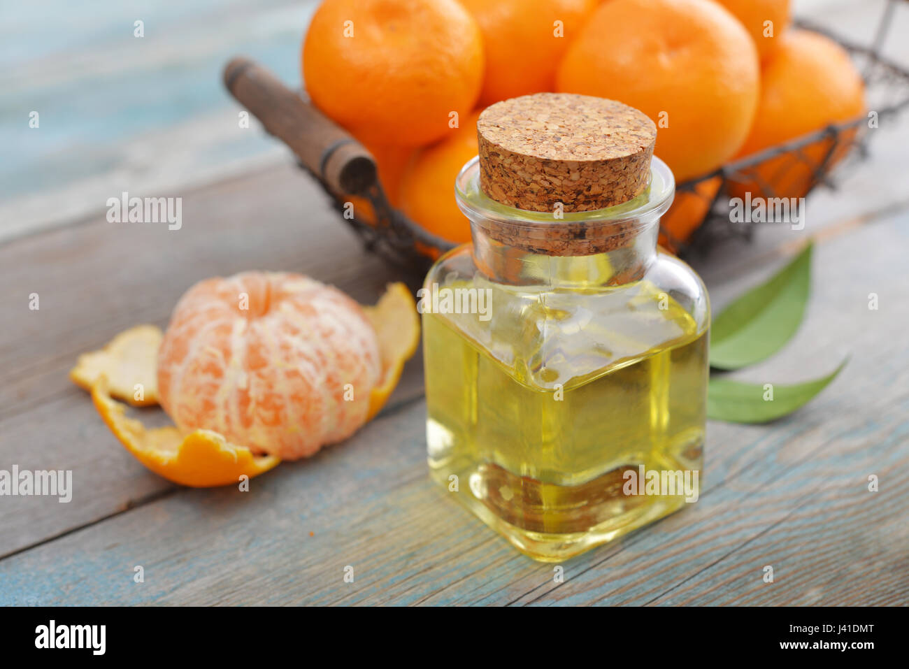 Tangerine olio essenziale in una bottiglia di vetro con freschi Mandarini on- sfondo di legno Foto Stock