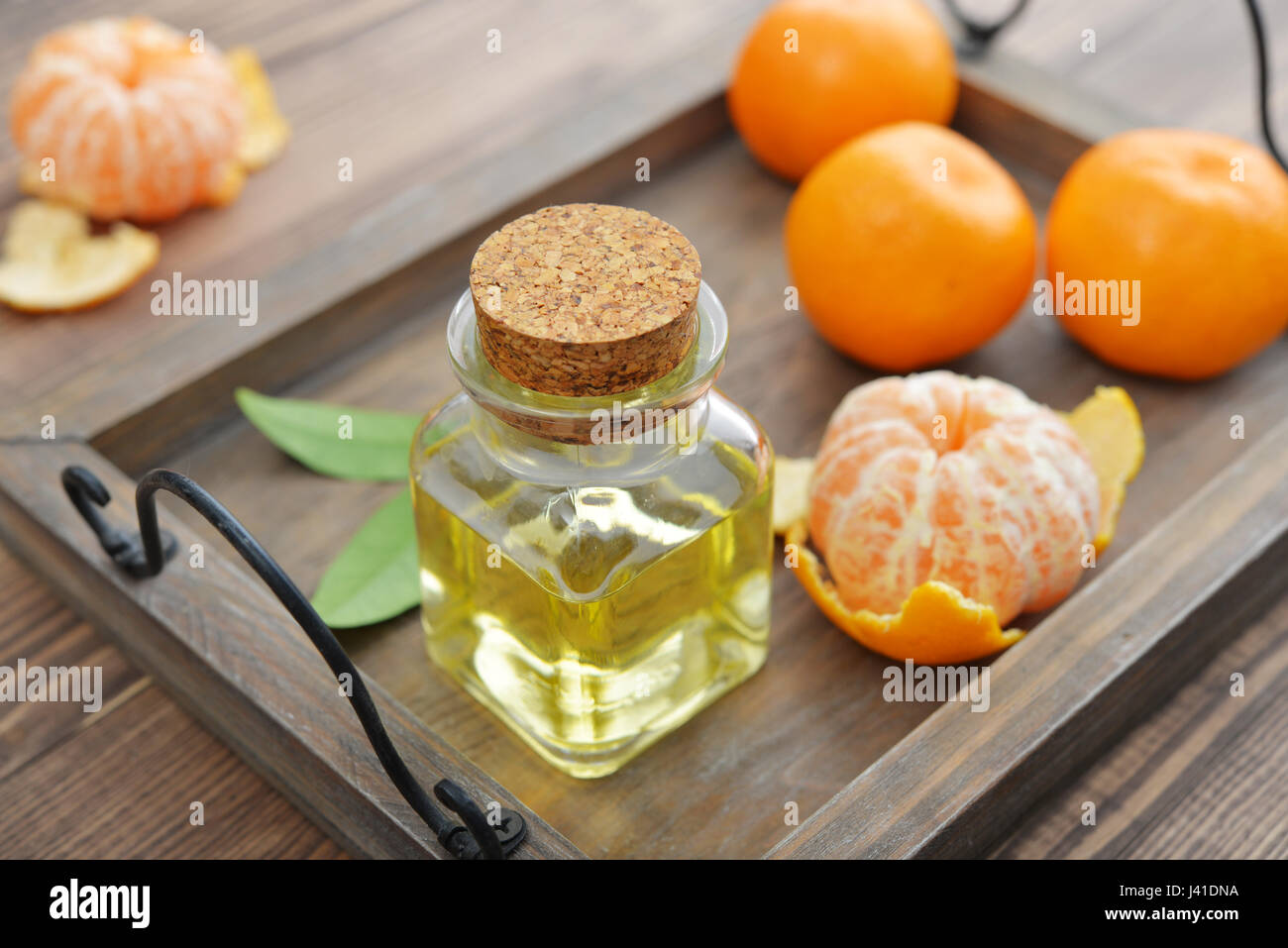 Tangerine olio essenziale in una bottiglia di vetro con freschi Mandarini su sfondo di legno Foto Stock