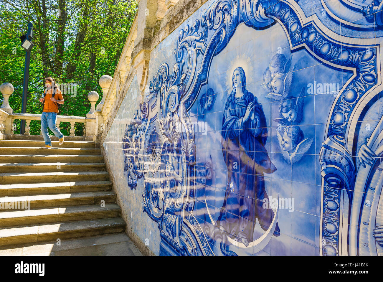 Il Portogallo piastrelle blu, un uomo discende l'Azulejos decorate scalinata barocca che conduce al di Nossa Senhora dos Remedios chiesa di Lamego, Portogallo Foto Stock