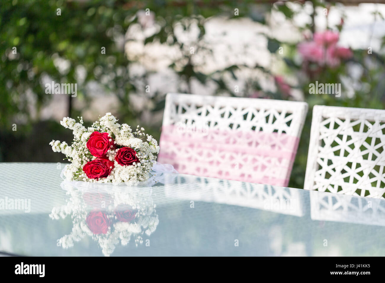 La tabella di matrimonio con rose rosa e sedie in giardino Foto Stock