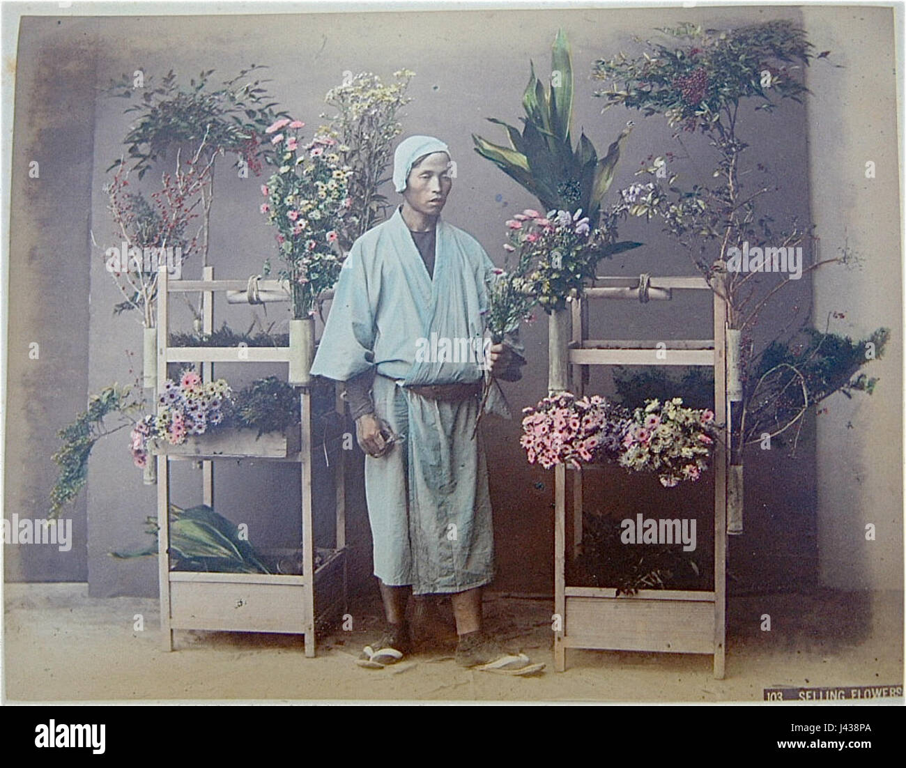 Questa fotografia di Kusakabe Kimbei presenta una scena di vendita di fiori, che cattura l'essenza del commercio tradizionale giapponese e della vita di strada durante l'era Meiji. Foto Stock