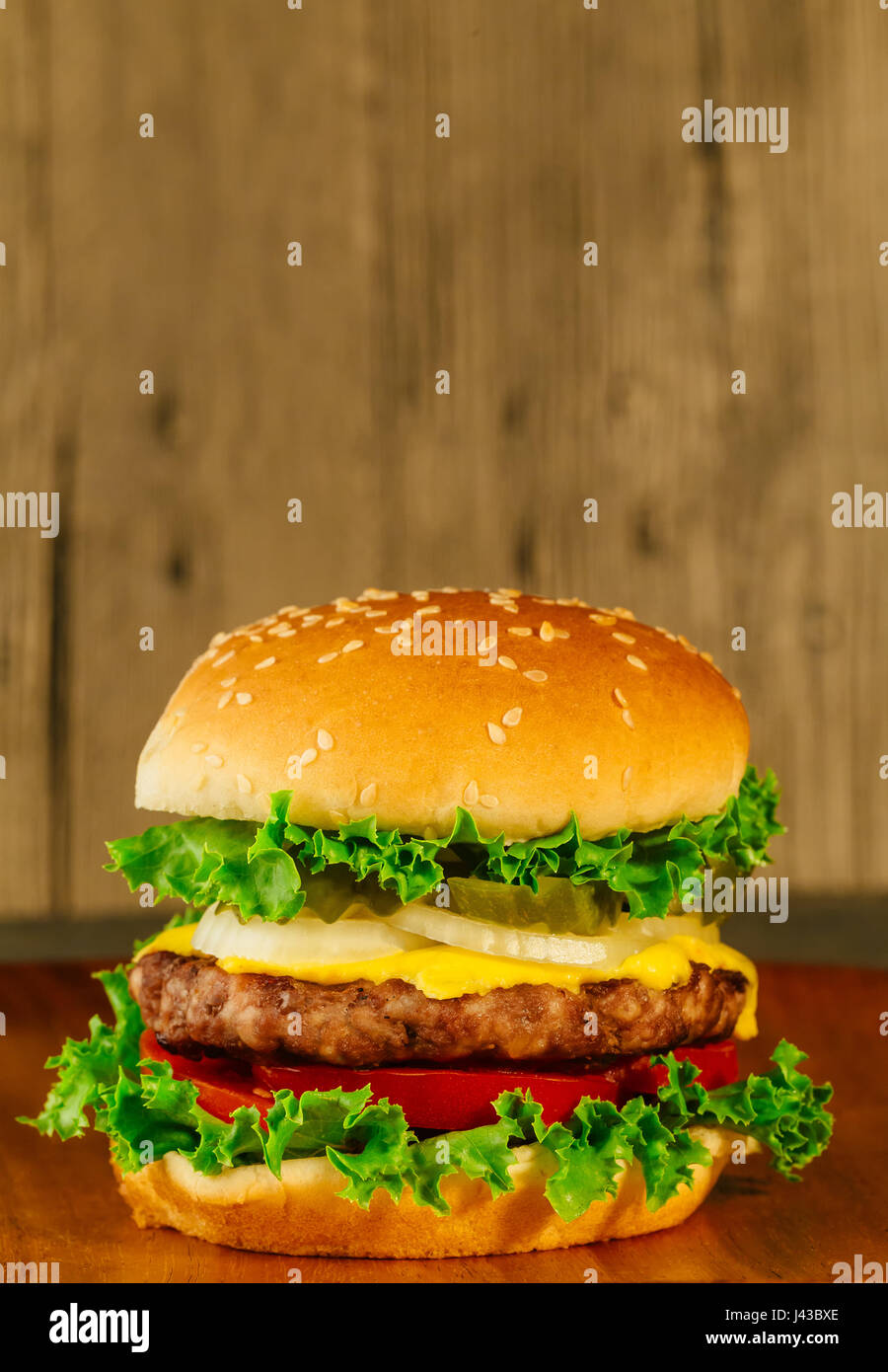 Camera classica deluxe cheeseburger con lattuga, cipolla, pomodoro e sottaceti su un seme di sesamo bun. Macro con shallow dof. Foto Stock