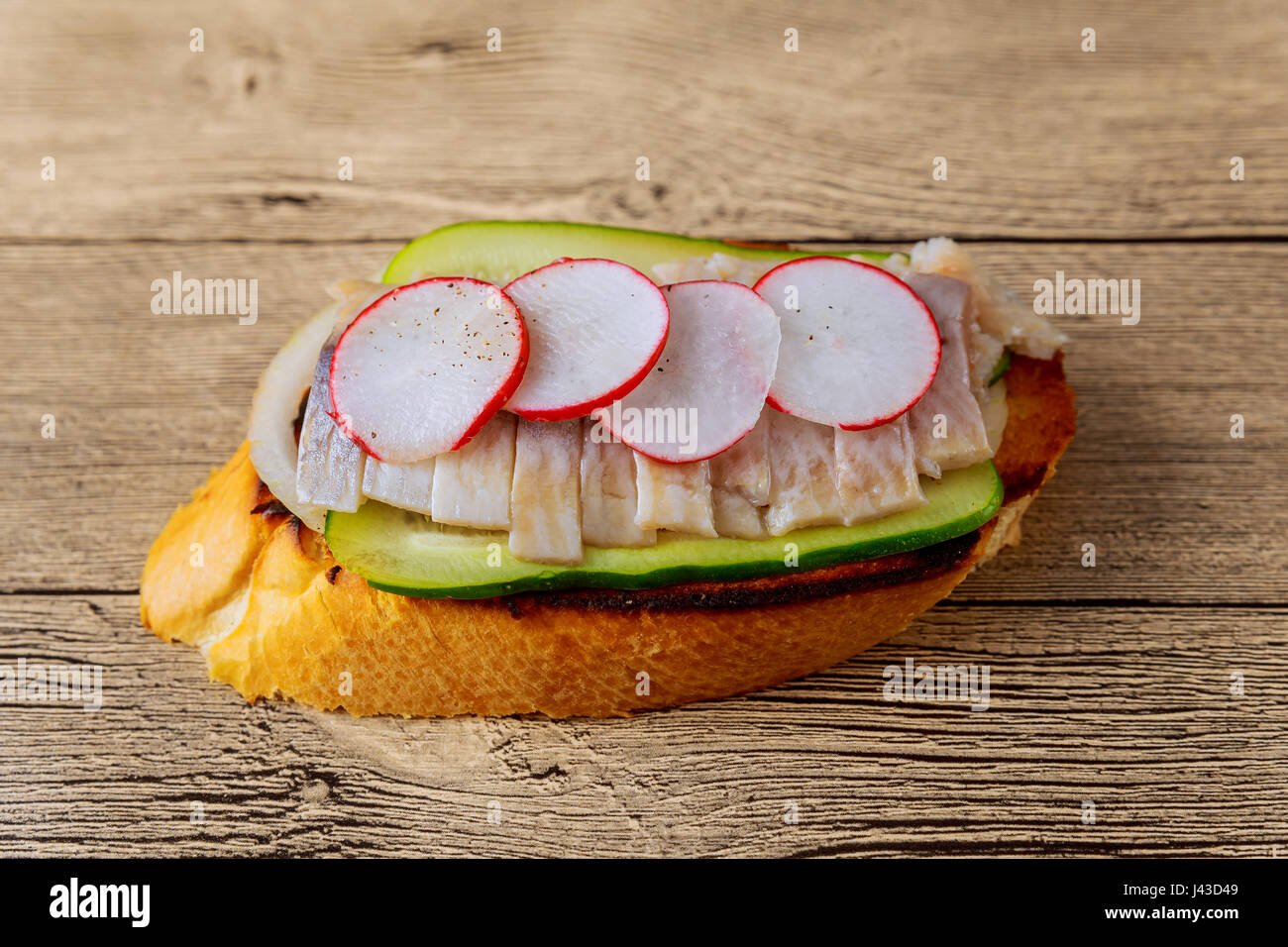 Piccoli panini con verdure, pesce cetriolo cipolla sandwich di rafano aringhe sfondo di legno. Vista dall'alto. Foto Stock