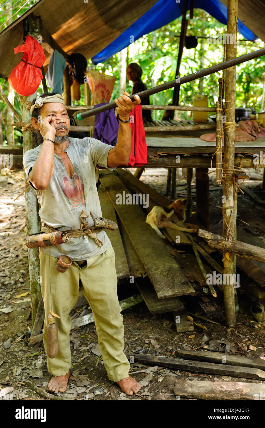 Lunga poso, BORNEO, Indonesia - 06 giugno 2011: Il nomade Punam dall'isola di Borneo è la preparazione di se stessi per sparare un colpo di pistola ad aria compressa per la monke Foto Stock